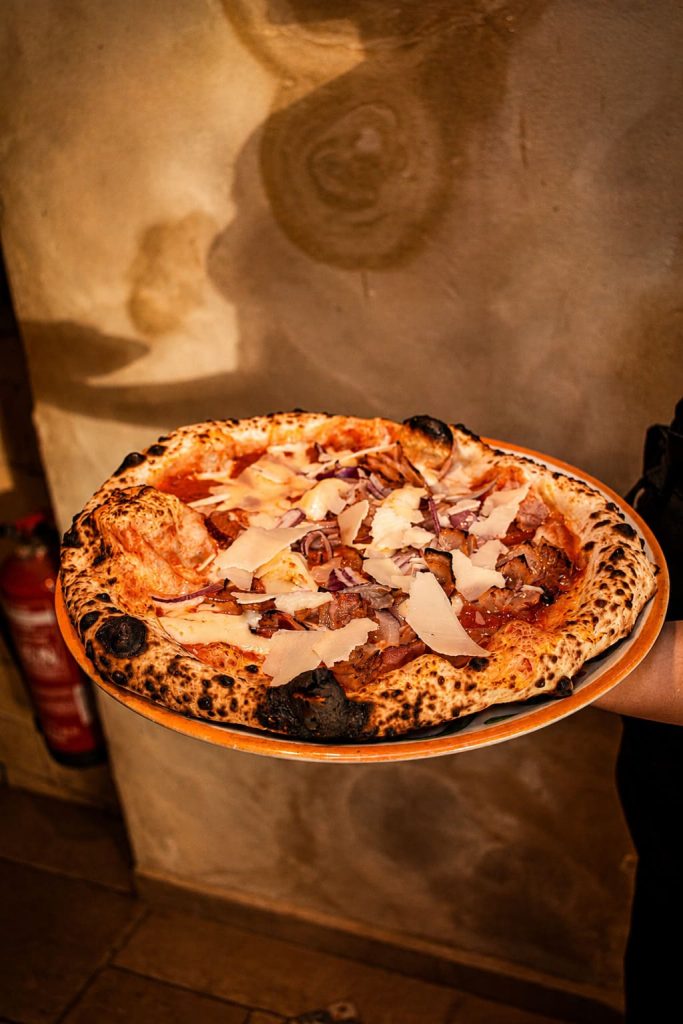 Pizza napolitana con jamón, cebolla morada y lascas de parmesano en La Trattoria de Tarifa